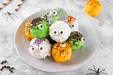 Homemade funny monster mini cakes or cake pops in a colored chocolate glaze and sugar sprinkles....
