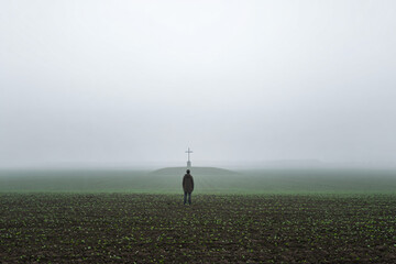 Fototapeta premium a person standing in a field with a cross on top of it