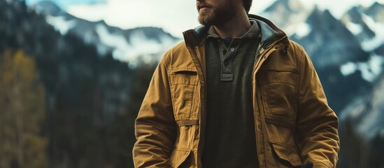 Man in mustard yellow jacket against mountain backdrop.