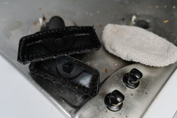 Top view of cleaning brush attachment for steam cleaner removing burned food from stove top,...