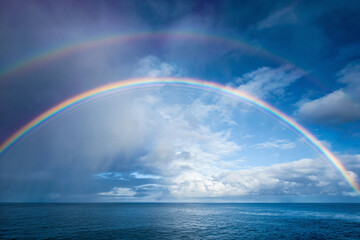 a rainbow over the ocean with a blue sky