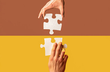 Human hands holds, putting together puzzle pieces. Two hands trying to connect couple puzzle piece