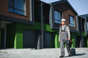 Master on call. A plumber or builder is standing near a house.