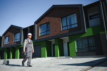 Master on call. A plumber or builder is standing near a house.