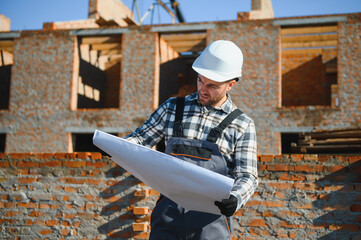 Portrait of a builder in the process of working on a construction site outdoors