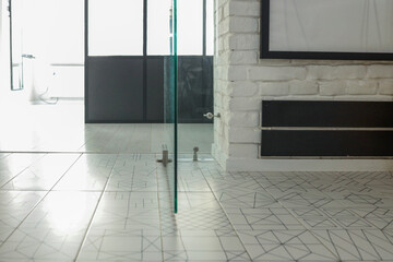 Interior view of a modern loft space with geometric tiled flooring, glass doors, white painted...