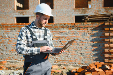 Portrait of a builder in the process of working on a construction site outdoors
