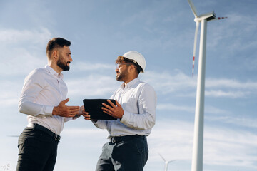 Two men engineers are on field, with wind turbines
