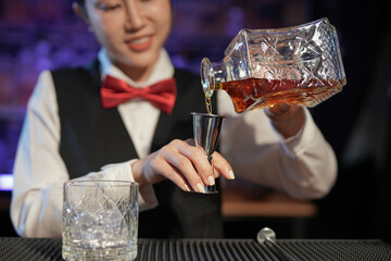 Professional female bartender preparing alcoholic drinks in a bar