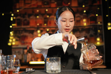 Professional female bartender preparing alcoholic drinks in a bar