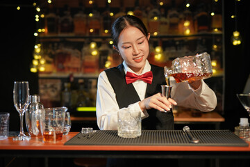 Professional female bartender preparing alcoholic drinks in a bar