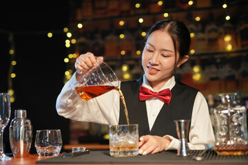 Professional female bartender preparing alcoholic drinks in a bar