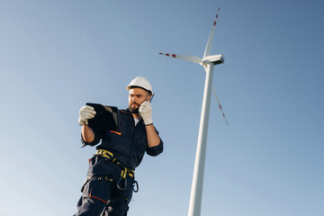 Speaking by walkie talkie. Engineer in field checking on wind turbine production