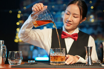 Professional female bartender preparing alcoholic drinks in a bar