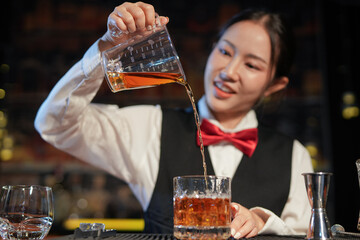 Professional female bartender preparing alcoholic drinks in a bar