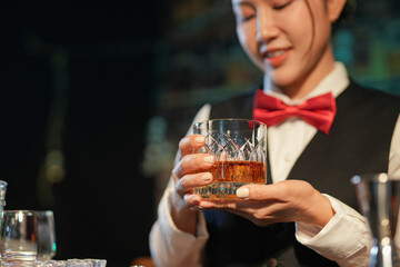 Professional female bartender preparing alcoholic drinks in a bar