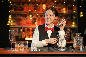 Professional female bartender preparing alcoholic drinks in a bar