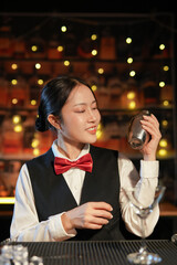 Professional female bartender preparing alcoholic drinks in a bar