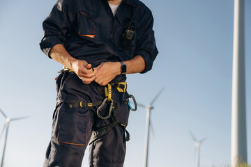 Detailed close up view of engineer in field with wind turbines against him