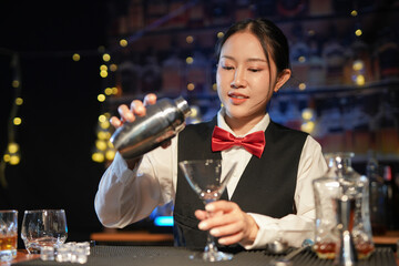 Professional female bartender preparing alcoholic drinks in a bar