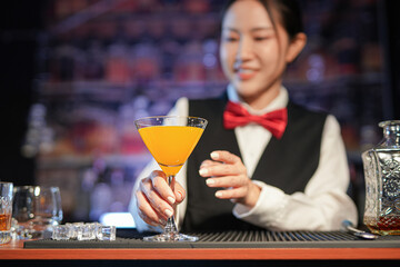 Professional female bartender preparing alcoholic drinks in a bar