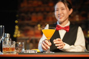 Professional female bartender preparing alcoholic drinks in a bar