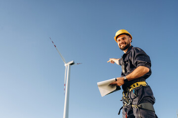 Documents in notepad. Engineer in field checking on wind turbine production