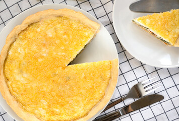 Appetizing homemade Quiche Lorraine with spinach and cheese on the kitchen table. Home cooking. Close-up. Top view.