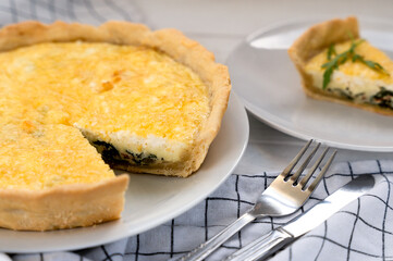 Close-up of freshly baked aromatic Quiche Lorraine with spinach and cheese on the table. Homemade baking. Close-up. Selective focus.