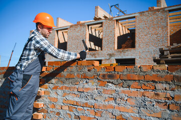 construction mason worker bricklayer installing red brick with trowel putty knife outdoors