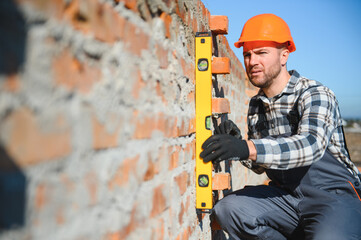 construction mason worker bricklayer installing red brick with trowel putty knife outdoors