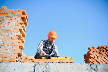 construction mason worker bricklayer installing red brick with trowel putty knife outdoors