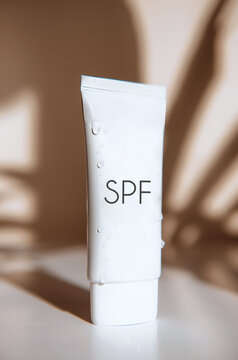 Sunscreen Tube with UVA and UVB Protection in jar on white table with sun light and shadow