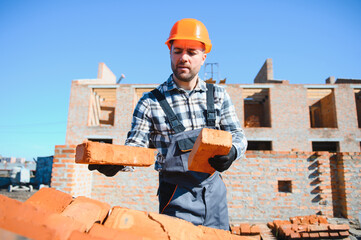 construction mason worker bricklayer installing red brick with trowel putty knife outdoors