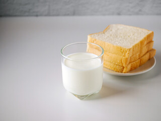 breakfast,Fresh milk in a glass and White sliced bread stacked on the white wooden table