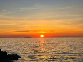 Serene sunset over the sea. The sun sets on the water. The sky is painted with bright colors. Sunny path on the water. Summer evening et sunset beach.