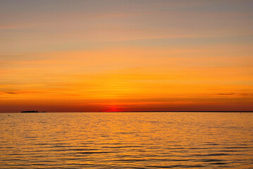 Calm sunset over the sea. The sky is painted with bright colors. Beautiful summer evening at the beach.