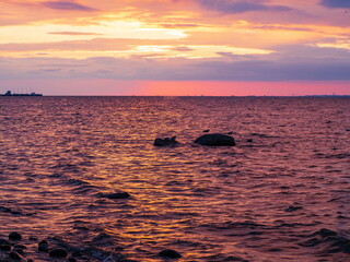 Scenic sunset on the sea. The sky is painted with bright colors. Cloudy summer evening