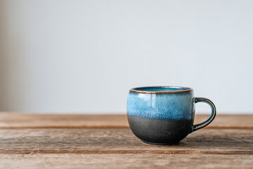 a blue and black coffee cup sitting on a wooden table