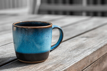 a blue and black coffee cup sitting on a wooden table