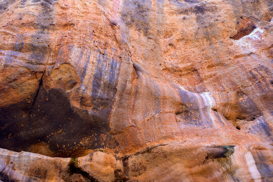Orange rock cliff face with purple striped pattern