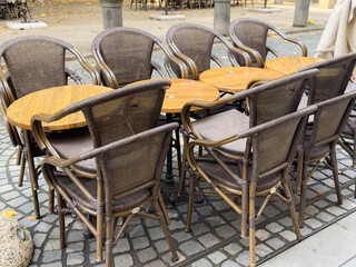 Ljubljana, Slovenia - July 06, 2025: Outdoor cafe scene featuring stacked wicker chairs and wooden...