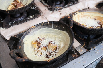 Sweet Indonesian martabak manis being prepared in small cast iron pans, topped with banana,...