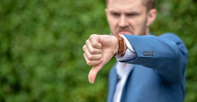 A man in a blue suit giving a thumbs down.