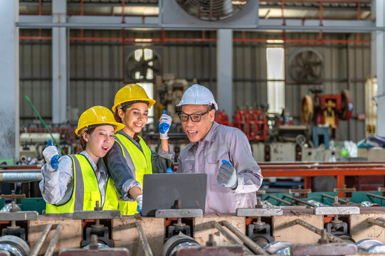 Friendly group of diverse industrial engineers wea yellow safety helmets and reflective vests discussing a project with a senior engineer in a manufactu factory setting - Powered by Adobe