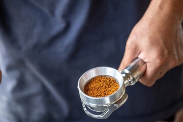 Close-up of a person's hand holding a metal scoop filled with vibrant orange turmeric powder over a dark fabric background, emphasizing natural spice selection and culinary use