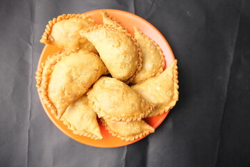 A plate full of crispy Indonesian pastel or Makassar-style jalangkote pastries, deep-fried and typically filled with vegetables or meat.