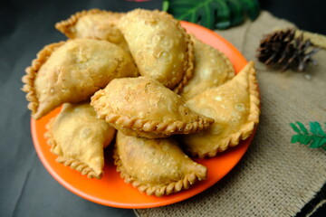 A plate full of crispy Indonesian pastel or Makassar-style jalangkote pastries, deep-fried and typically filled with vegetables or meat.