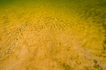 Detail shot of water with ripples and green and yellow tones