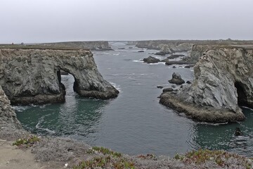 Coastal landscape with dramatic rock formations.  Ocean inlet with arches